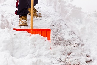 person wearing boots shoveling snow