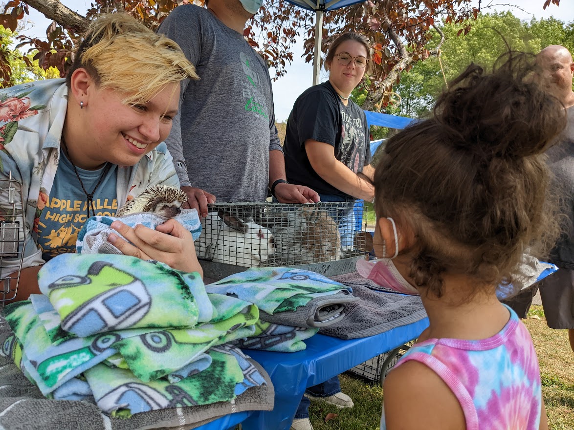 DCFC staff and a community member share smiles while petting a hedgehog